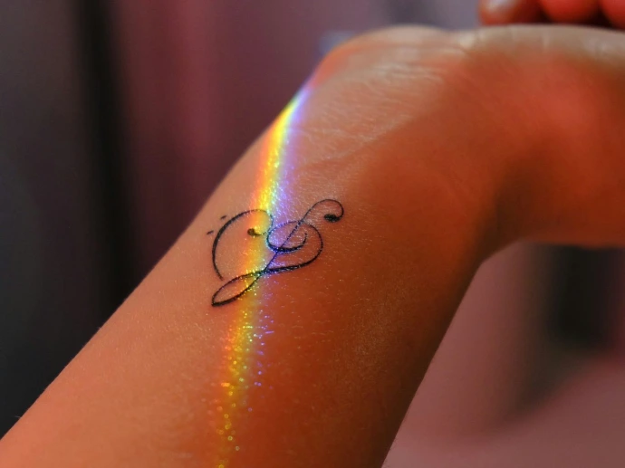 A person with a rainbow tattoo on their arm